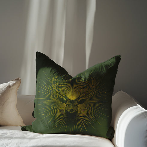 A pillow cover with a majestic stag illustrated in metallic gold on deep moss green fabric. Gleaming rays extend outward from the deer's head, with small golden stars dispersed throughout.